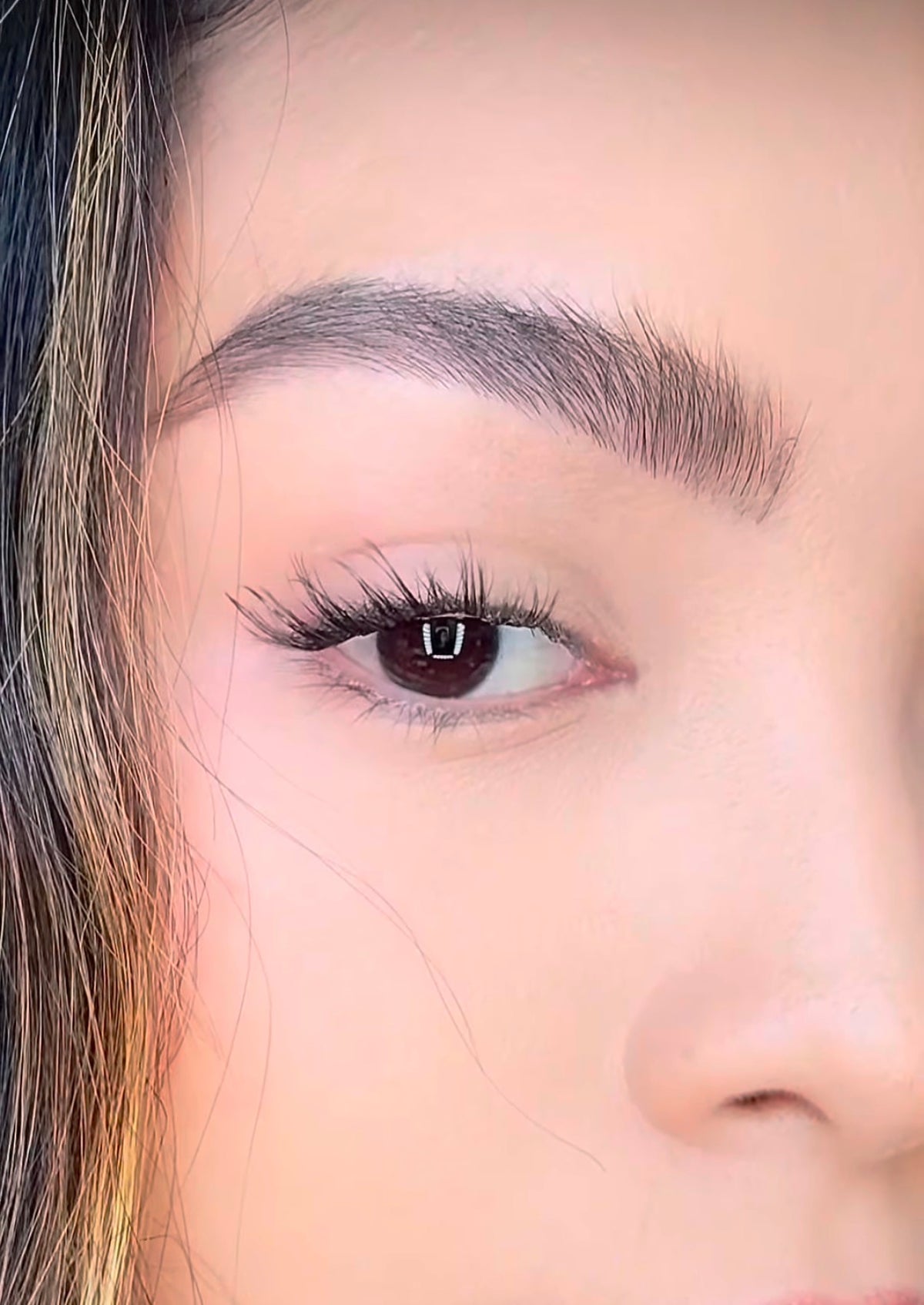 Woman applying ONYX Lash Australia cluster lashes in Socialite